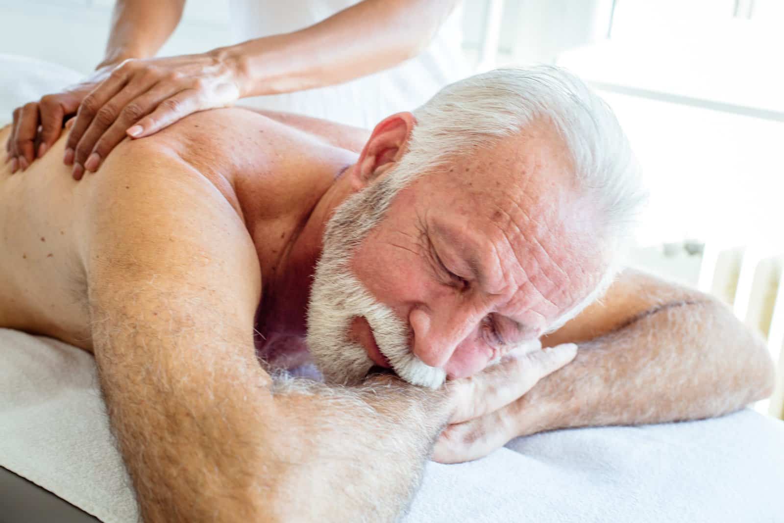Older adult receiving a gentle shoulder and upper-back massage